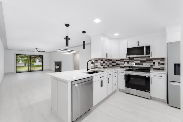 kitchen featuring ceiling fan, sink, kitchen peninsula, decorative light fixtures, and appliances with stainless steel finishes