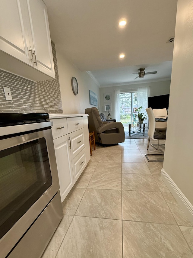 kitchen with range, backsplash, white cabinetry, and ceiling fan