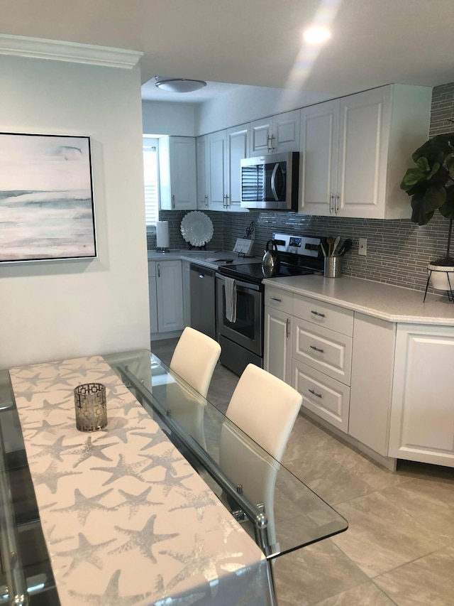 kitchen with white cabinetry, ornamental molding, appliances with stainless steel finishes, and tasteful backsplash