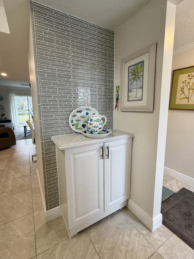 interior space featuring a textured ceiling, tile patterned floors, tile walls, and crown molding