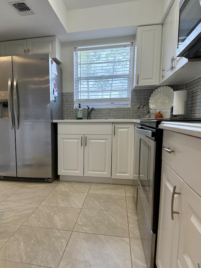 kitchen featuring backsplash, sink, light tile patterned floors, white cabinetry, and stainless steel appliances