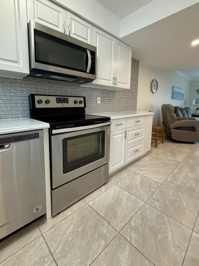 kitchen featuring appliances with stainless steel finishes, backsplash, crown molding, light tile patterned floors, and white cabinetry