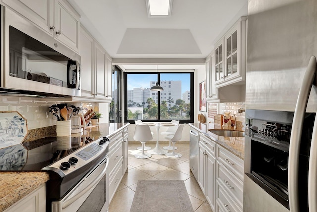 kitchen featuring white cabinetry, sink, a raised ceiling, backsplash, and appliances with stainless steel finishes