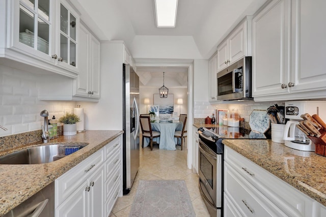 kitchen with appliances with stainless steel finishes, tasteful backsplash, sink, white cabinets, and hanging light fixtures