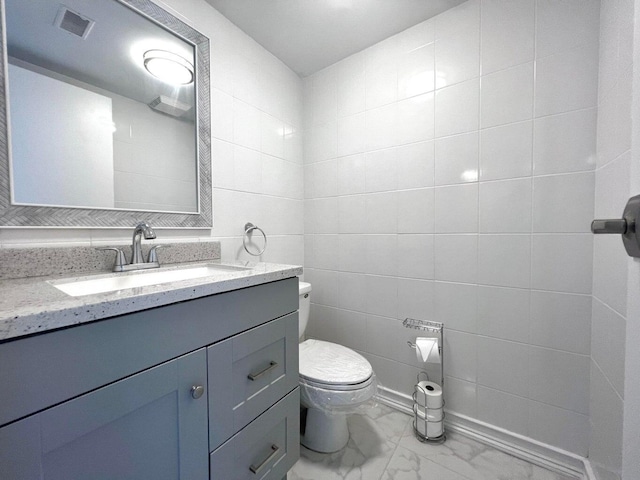 bathroom with vanity, toilet, and tile walls