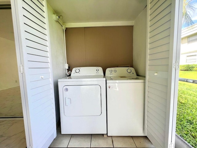 clothes washing area with washer and dryer, a healthy amount of sunlight, and light tile patterned flooring