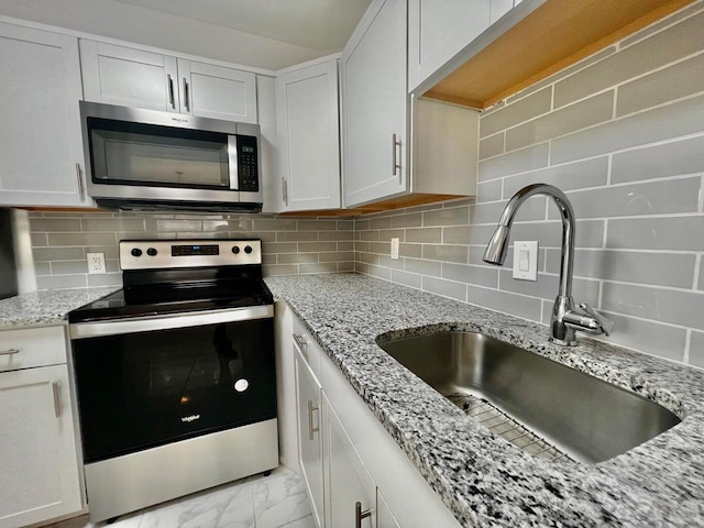 kitchen with backsplash, white cabinetry, sink, and appliances with stainless steel finishes