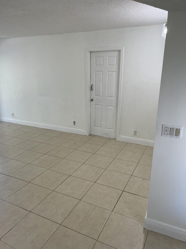 spare room with light tile patterned floors and a textured ceiling