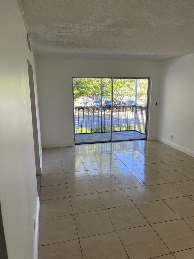 empty room with light tile patterned flooring and a textured ceiling