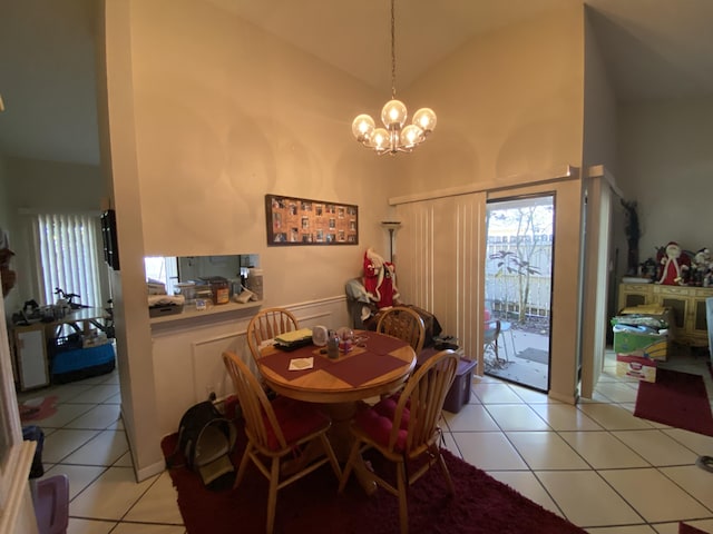 tiled dining room featuring a notable chandelier and high vaulted ceiling