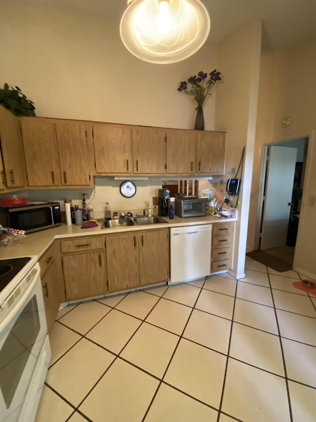 kitchen with light tile patterned floors, white appliances, sink, and a towering ceiling