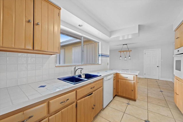 kitchen with white appliances, sink, tasteful backsplash, light tile patterned flooring, and kitchen peninsula