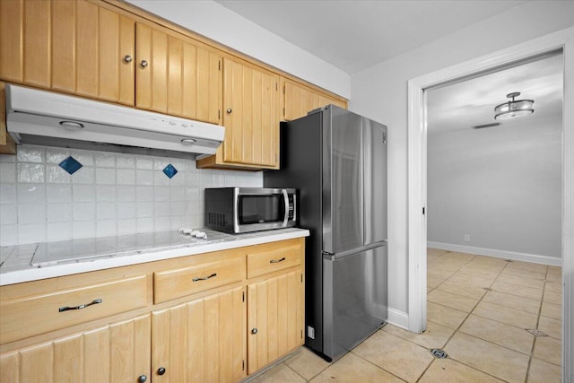 kitchen featuring light brown cabinets, stainless steel appliances, tasteful backsplash, and light tile patterned flooring