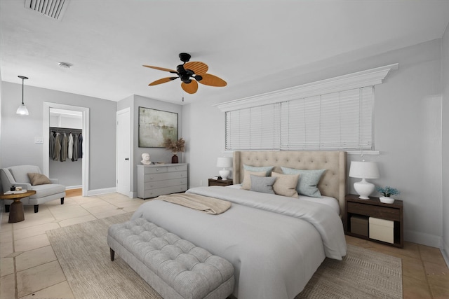 tiled bedroom featuring ceiling fan, a walk in closet, and a closet