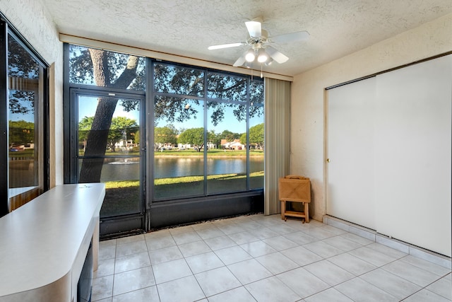 unfurnished sunroom featuring a water view and ceiling fan