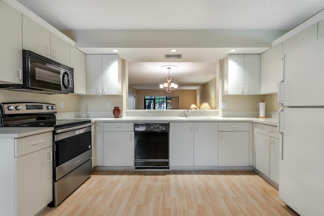 kitchen with white cabinetry, hanging light fixtures, light hardwood / wood-style flooring, and black appliances