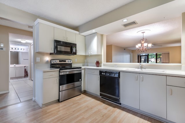 kitchen with pendant lighting, sink, a notable chandelier, black appliances, and a textured ceiling