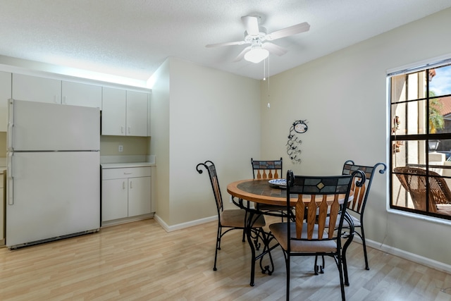 dining space featuring a textured ceiling, ceiling fan, and light hardwood / wood-style flooring