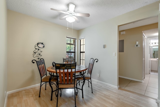 dining area with ceiling fan, light hardwood / wood-style flooring, and a textured ceiling