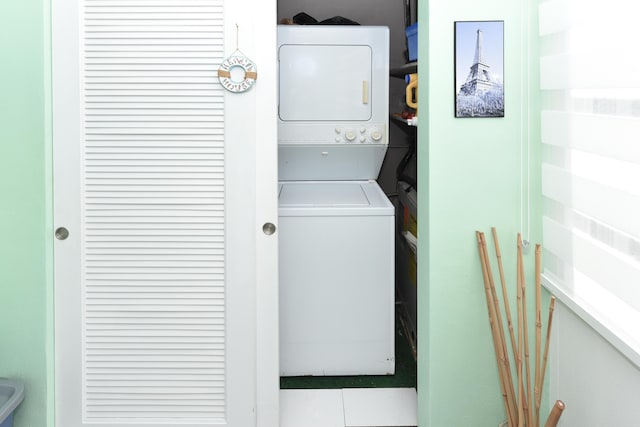 clothes washing area featuring light tile patterned floors and stacked washer / dryer