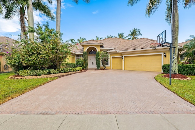 mediterranean / spanish home featuring a front yard and a garage