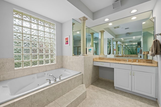 bathroom with tiled bath, ornate columns, plenty of natural light, and vanity