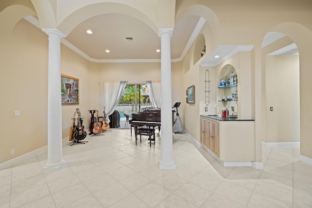 interior space featuring light tile patterned floors, decorative columns, ornamental molding, and sink