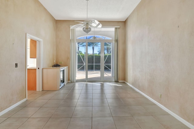 unfurnished dining area with ceiling fan, light tile patterned floors, a textured ceiling, and french doors