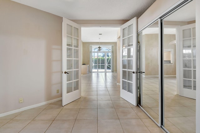 hallway with light tile patterned floors, a textured ceiling, and french doors