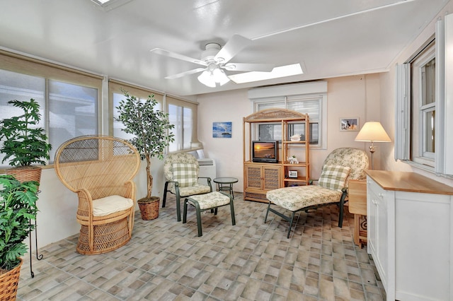 sitting room with a skylight, ceiling fan, and light hardwood / wood-style floors