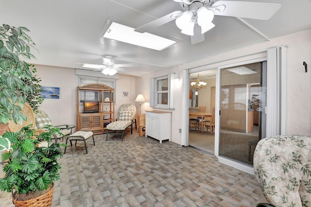 living area featuring carpet flooring, ceiling fan with notable chandelier, and a skylight