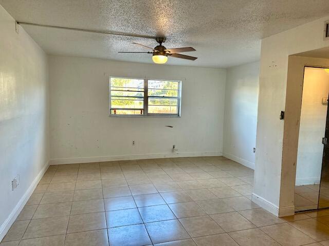 tiled spare room with a textured ceiling and ceiling fan