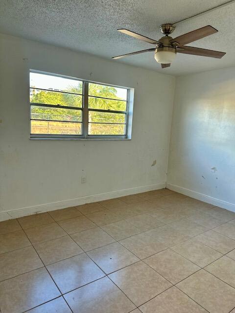 tiled spare room with ceiling fan and a textured ceiling