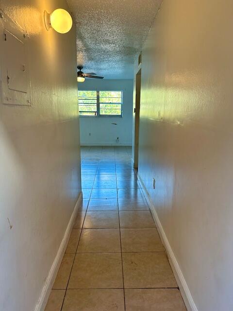 corridor with light tile patterned floors and a textured ceiling