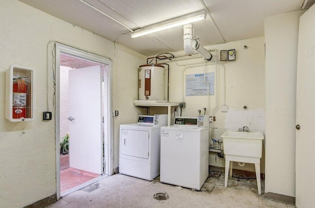 clothes washing area with sink, separate washer and dryer, and water heater