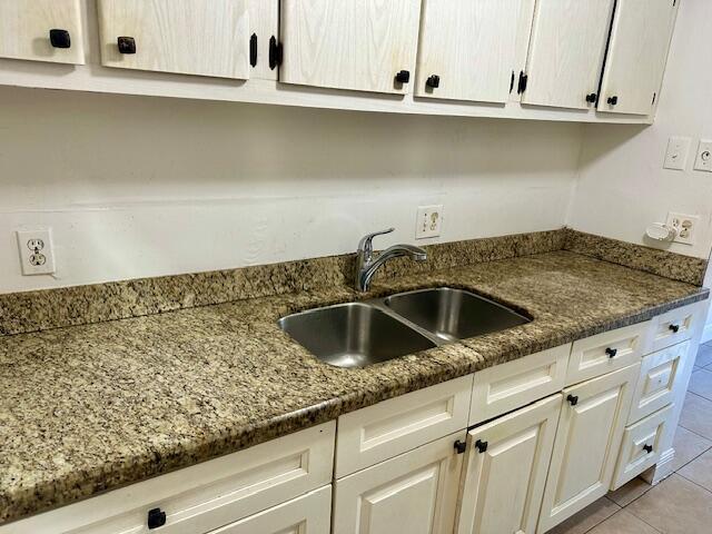 kitchen with light tile patterned floors, dark stone countertops, and sink