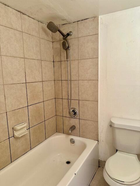 bathroom with tiled shower / bath combo and toilet