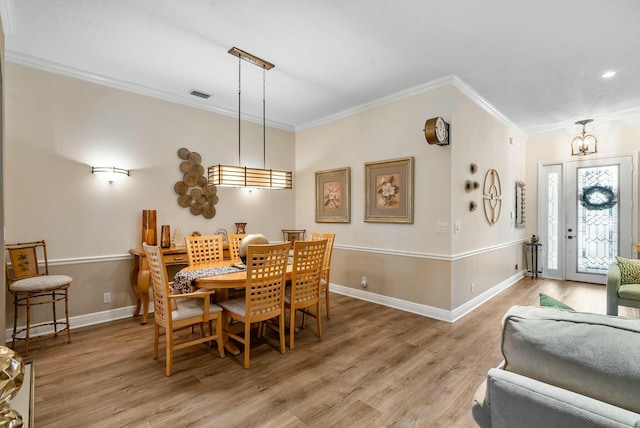 dining area featuring crown molding, light hardwood / wood-style floors, and a notable chandelier