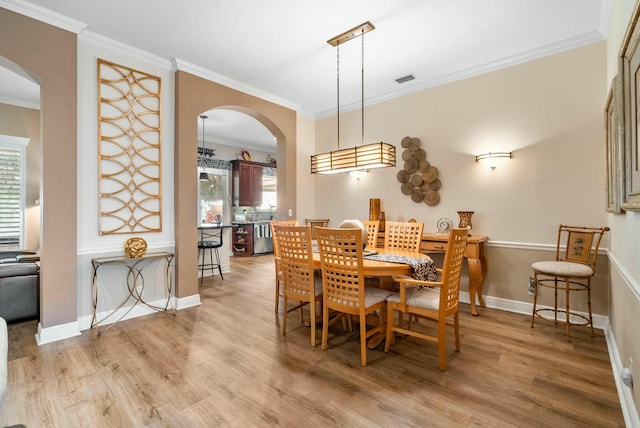 dining room with crown molding and light hardwood / wood-style flooring