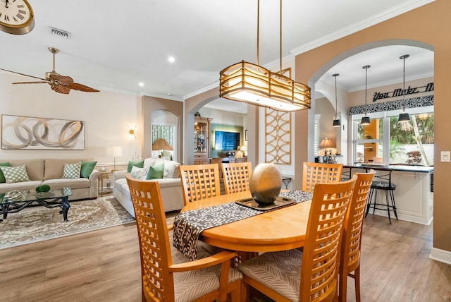 dining space featuring light wood-type flooring, ceiling fan, and ornamental molding