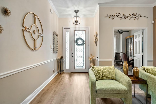 foyer featuring a healthy amount of sunlight, ceiling fan with notable chandelier, hardwood / wood-style flooring, and ornamental molding