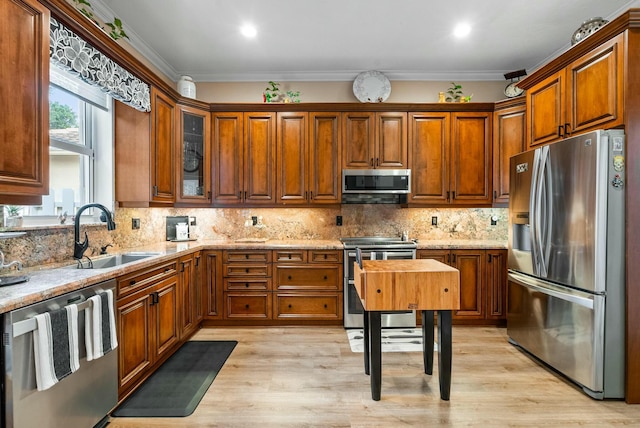 kitchen featuring light stone counters, ornamental molding, sink, and appliances with stainless steel finishes