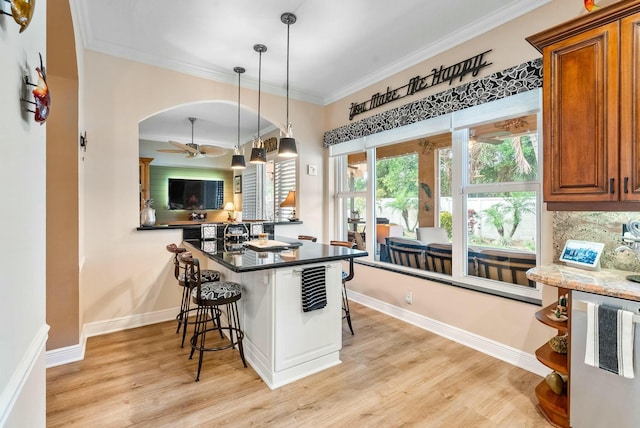 kitchen with a kitchen bar, crown molding, pendant lighting, and light wood-type flooring