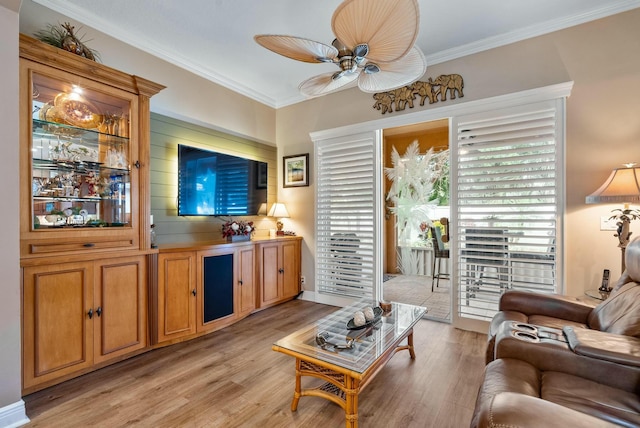 living room featuring light hardwood / wood-style floors, ceiling fan, and crown molding