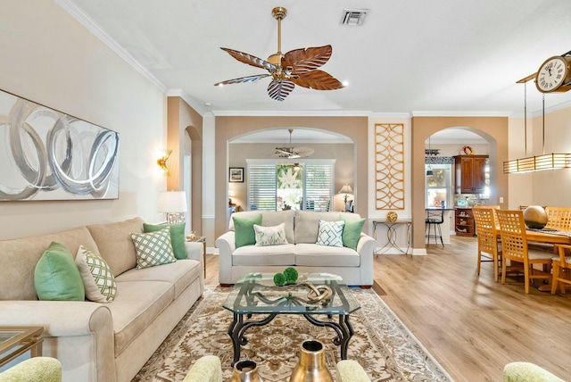 living room featuring crown molding, ceiling fan with notable chandelier, and light wood-type flooring