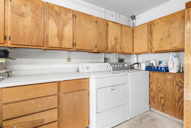 clothes washing area with separate washer and dryer, cabinets, and a textured ceiling