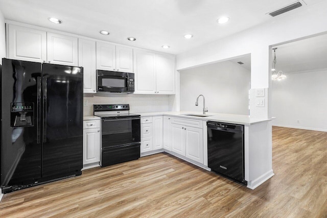 kitchen with sink, kitchen peninsula, light hardwood / wood-style floors, white cabinets, and black appliances