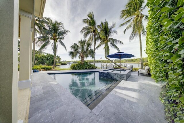 view of swimming pool featuring an in ground hot tub, a patio, and a water view