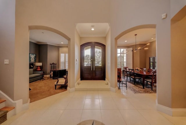 foyer with crown molding, french doors, and light tile patterned floors