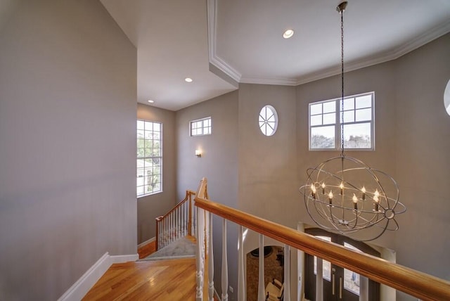 stairs featuring an inviting chandelier, wood-type flooring, and ornamental molding